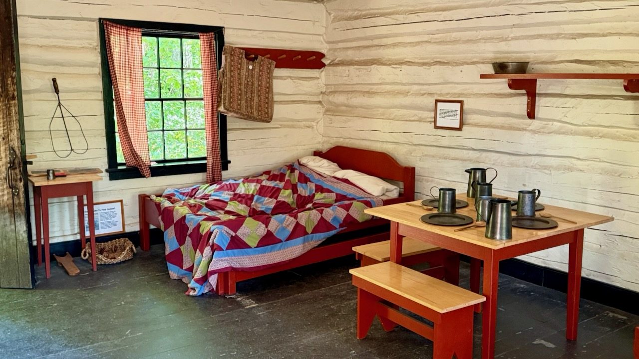 A restored room at Fort Wilkins with a quilted bed and a table set for a meal